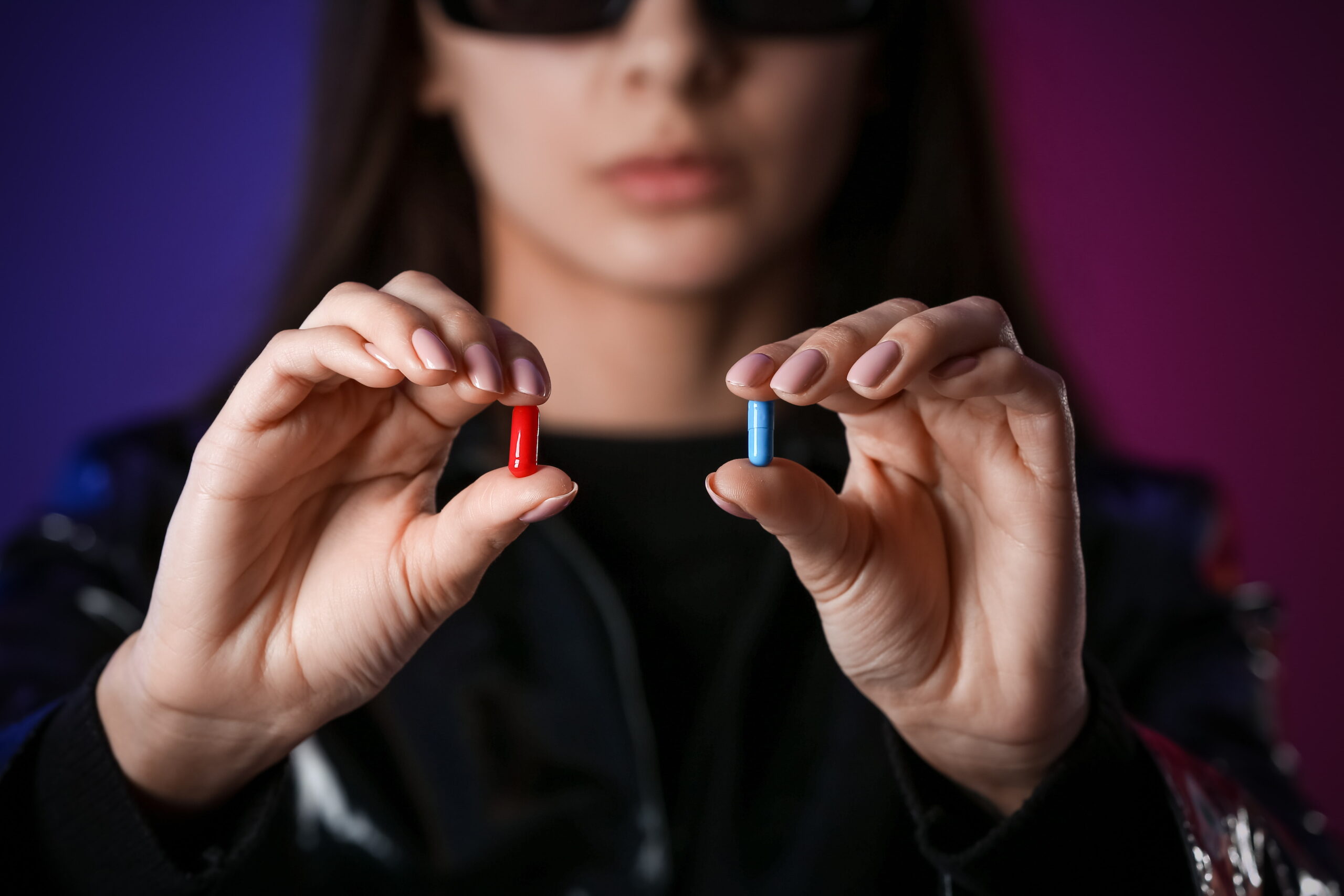 Close-up of a person holding a red pill in one hand and a blue pill in the other, referencing the iconic choice from The Matrix movie. The red pill symbolizes uncovering the truth about the extracellular matrix's involvement in aging, while the blue pill represents remaining unaware of these biological processes. The image creates a thought-provoking metaphor for readers, inviting them to explore the science behind aging and potential interventions.