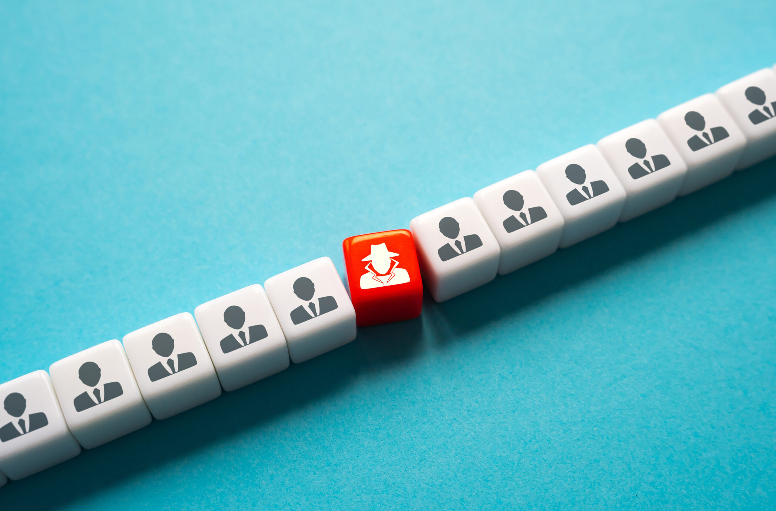 A row of white cubes with icons of people in suits, symbolizing uniform individuals, with a single red cube depicting a figure in a hat and trench coat, representing an undercover or hidden character among the crowd. This visually highlights the concept of an infiltrator or hidden element within a larger group, akin to the role of cancer-associated fibroblasts (CAFs) supporting tumor growth in the tumor microenvironment.