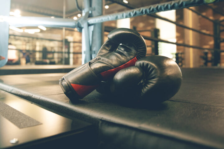 Black boxing gloves resting on a boxing ring mat in a gym, symbolizing the fight against age-related muscle loss as highlighted in the article 'How to Understand and Combat Age-Related Muscle Loss.