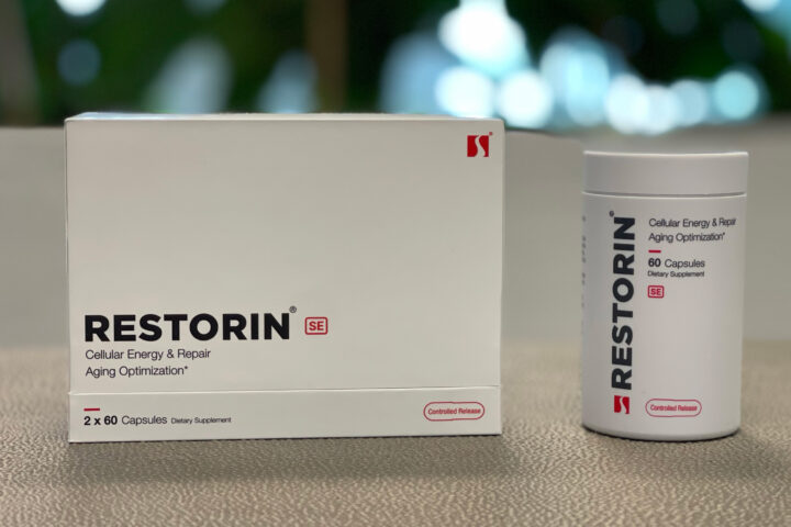 A promotional image showcasing the RESTORIN® product packaging and bottle. The white box with bold black text "RESTORIN SE" and the accompanying bottle labeled "Cellular Energy & Repair Aging Optimization" are placed on a neutral surface, with a blurred natural background that emphasizes innovation and health. The sleek, minimalist design of the packaging highlights RESTORIN®'s focus on advanced scientific research targeting the root causes of aging, including mTOR modulation, senolytics, and sirtuin activation.