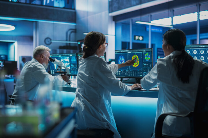 Scientists in a futuristic laboratory analyzing brain scans and cellular data on advanced monitors, with a focus on cutting-edge research and biomedical innovation. The scene emphasizes teamwork, advanced technology, and longevity science.