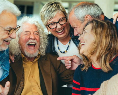 A diverse group of joyful older adults laughing and sharing a moment together, highlighting the importance of social engagement for healthy aging and mental well-being, as emphasized in the blog post about the benefits of staying socially connected.