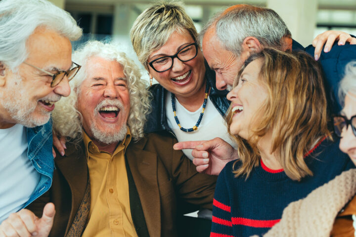 A diverse group of joyful older adults laughing and sharing a moment together, highlighting the importance of social engagement for healthy aging and mental well-being, as emphasized in the blog post about the benefits of staying socially connected.