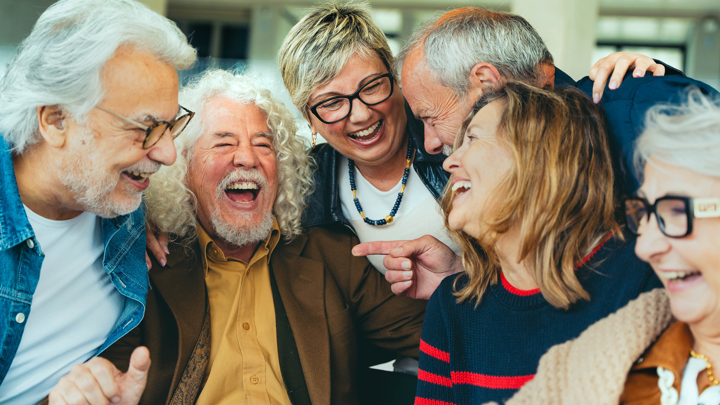 A diverse group of joyful older adults laughing and sharing a moment together, highlighting the importance of social engagement for healthy aging and mental well-being, as emphasized in the blog post about the benefits of staying socially connected.