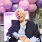 Ethel Caterham, the world’s oldest living person in 2025 at age 115, smiles while celebrating her birthday at a care home in Surrey, England. Surrounded by pink and purple balloons, she embodies calm and independence—traits she credits for her longevity.