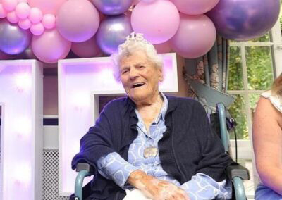 Ethel Caterham, the world’s oldest living person in 2025 at age 115, smiles while celebrating her birthday at a care home in Surrey, England. Surrounded by pink and purple balloons, she embodies calm and independence—traits she credits for her longevity.