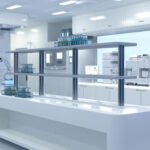 An image of a white, futuristic lab, with articulated robotic arms in the background.