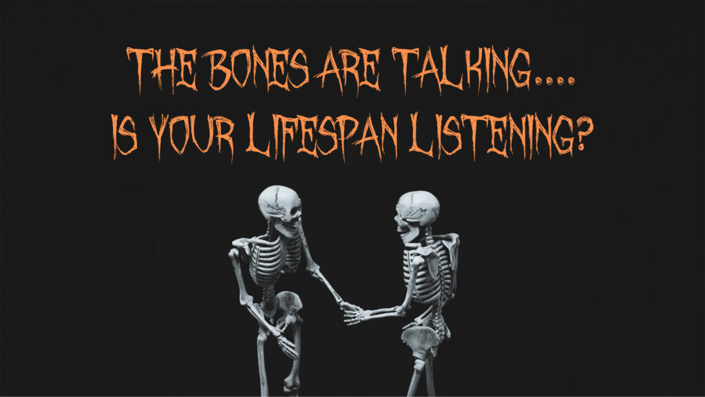 An image of two skeletons shaking hands and conversing in front of a black background. Above their skeleton skulls, a spooky, haunting font with sharp lines and jagged edges reads "The Bones Are Talking... Is Your Lifespan Listening?"